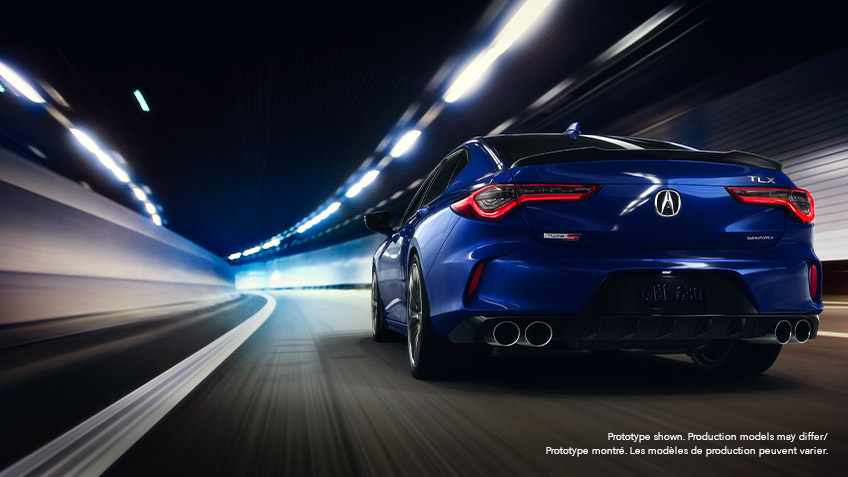 Rear view of a blue Acura TLX driving down a roadway at night, surrounded by city lights blurred by motion.	Vue arrière d’une Acura TLX bleue roulant à pleine vitesse la nuit sur une route bordée de néons.